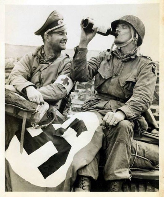 A rescued member of the 82nd Airborne captured during the D-Day drops drinks some 'liberated' wine while a medic with captured German items enjoys the levity of the moment. France 1944.jpg